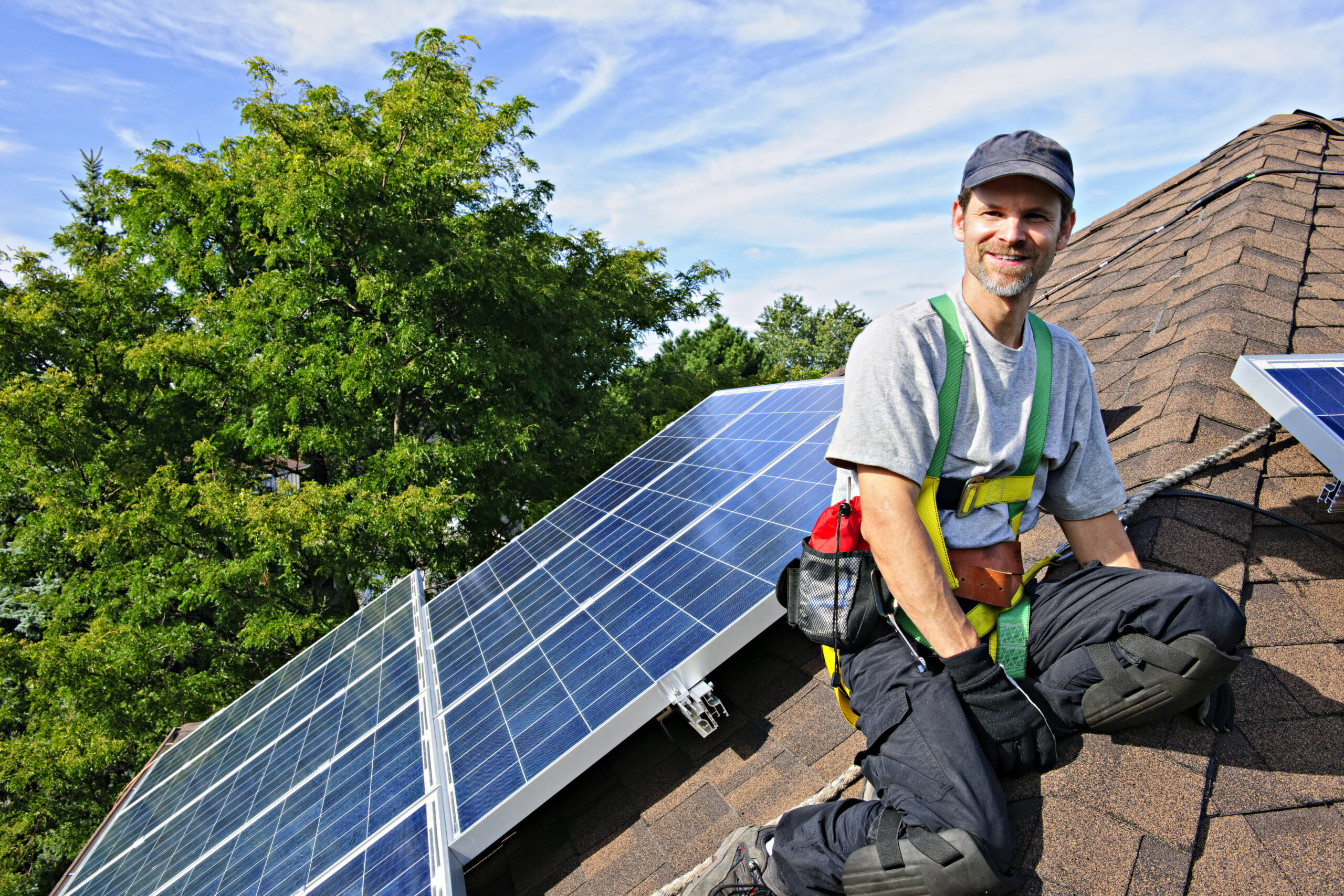 Man installing alternative energy photovoltaic solar panels on roof denten insurance contractor